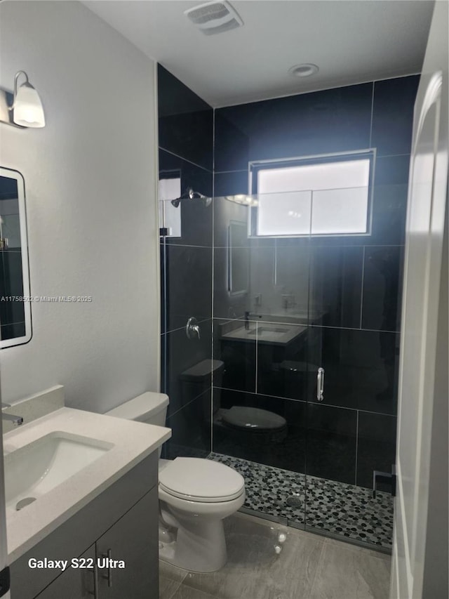 full bathroom featuring toilet, a shower stall, visible vents, and vanity