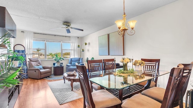 dining room with a textured ceiling, wood finished floors, and ceiling fan with notable chandelier