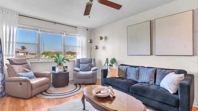 living room with a ceiling fan, a textured ceiling, and wood finished floors