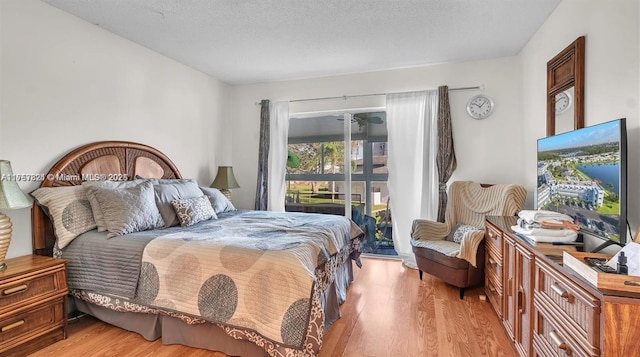 bedroom with a textured ceiling, light wood-style flooring, and access to exterior