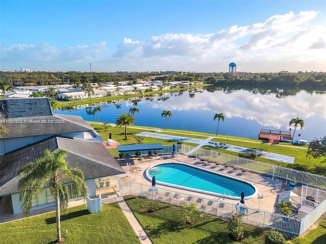 community pool with a water view, fence, and a patio