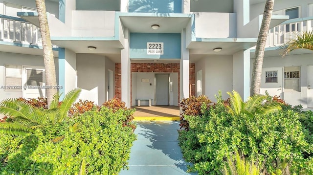 view of exterior entry featuring brick siding and stucco siding