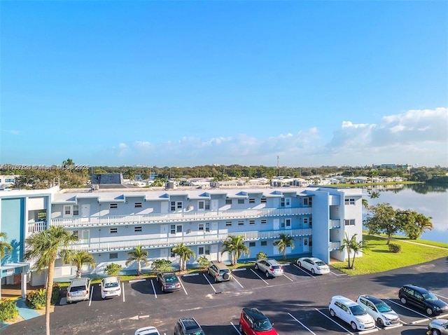 view of building exterior with a water view, uncovered parking, and a residential view