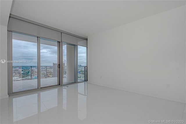 empty room featuring floor to ceiling windows, baseboards, and tile patterned floors