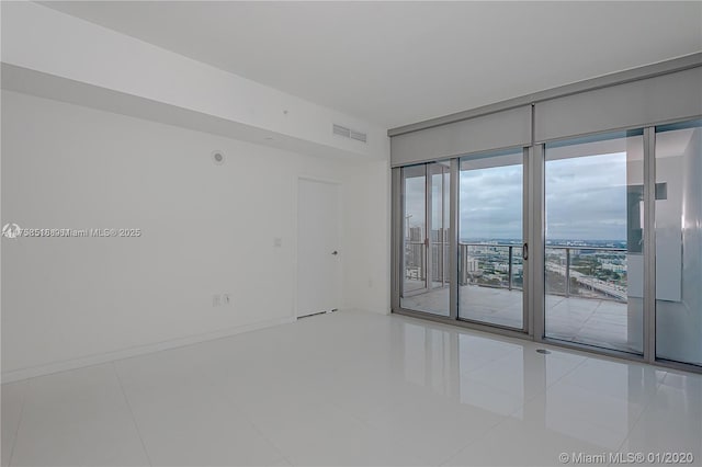 empty room featuring visible vents, baseboards, and tile patterned floors