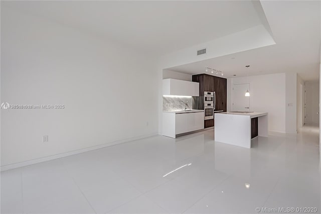 kitchen featuring a kitchen island, visible vents, light countertops, modern cabinets, and decorative light fixtures