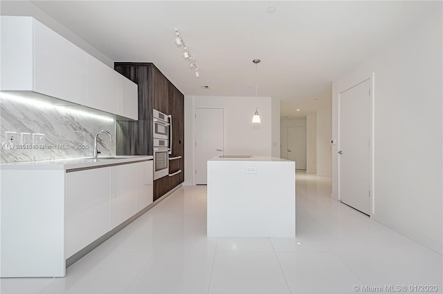 kitchen with a sink, white cabinetry, a center island, decorative backsplash, and modern cabinets