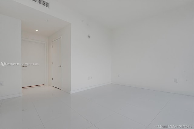 tiled empty room with visible vents and baseboards