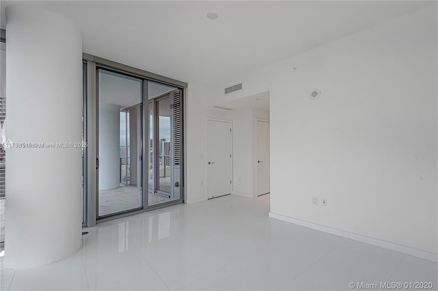 spare room with a wall of windows, visible vents, and baseboards