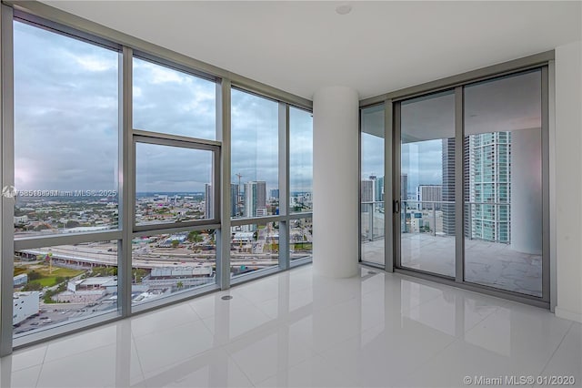 tiled empty room featuring expansive windows, a city view, and plenty of natural light