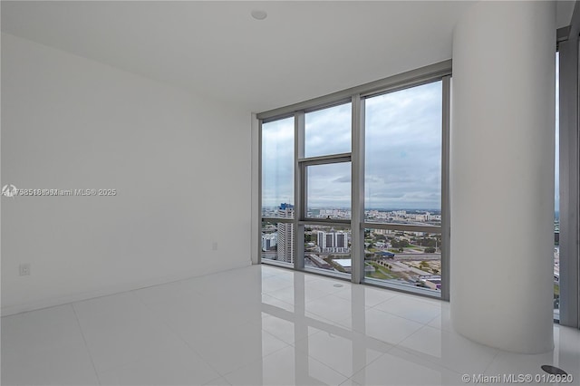 unfurnished room featuring a wall of windows, a view of city, and tile patterned floors