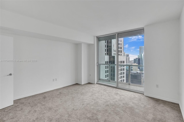 empty room featuring carpet floors, baseboards, a wall of windows, and a city view