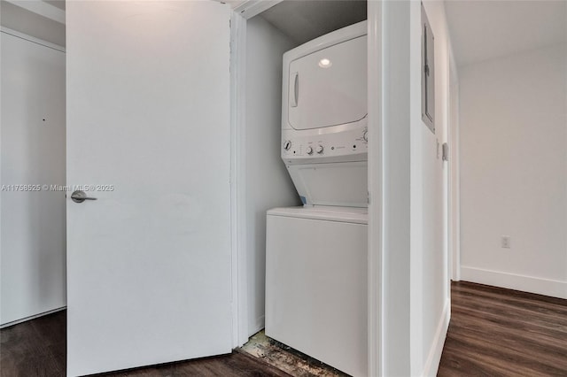 laundry area with laundry area, stacked washer / dryer, wood finished floors, and baseboards