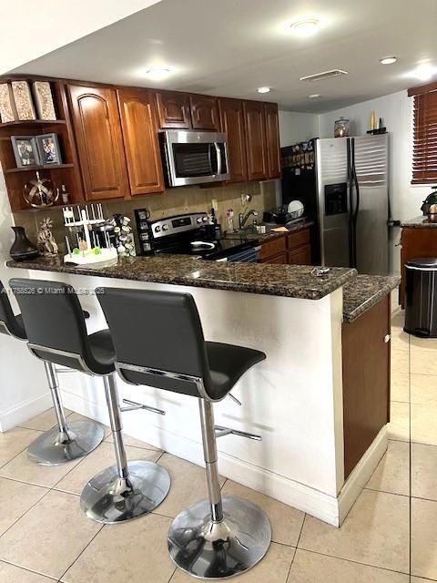 kitchen with stainless steel appliances, a kitchen breakfast bar, and light tile patterned floors