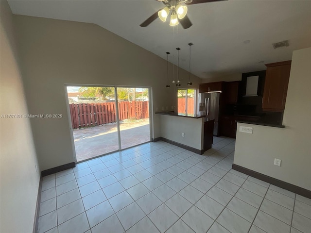 kitchen featuring light tile patterned floors, stainless steel fridge, visible vents, dark countertops, and a peninsula