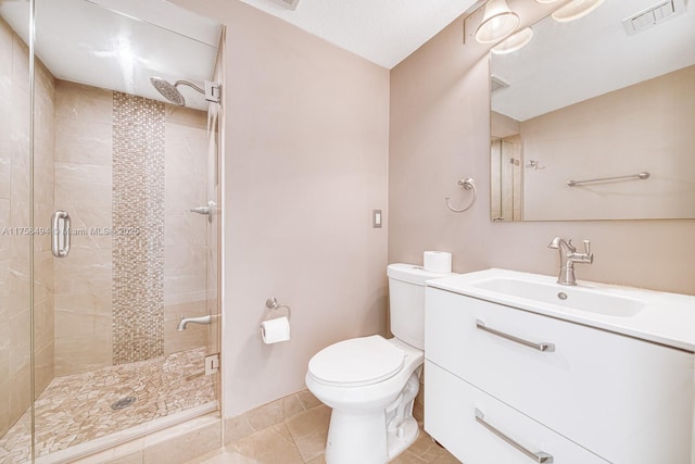 bathroom featuring toilet, vanity, visible vents, tile patterned floors, and a stall shower