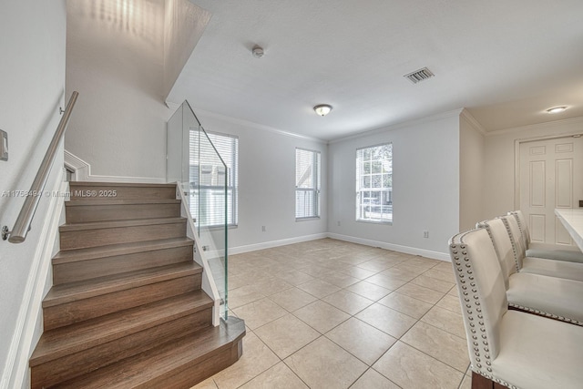 stairway with tile patterned flooring, visible vents, crown molding, and baseboards