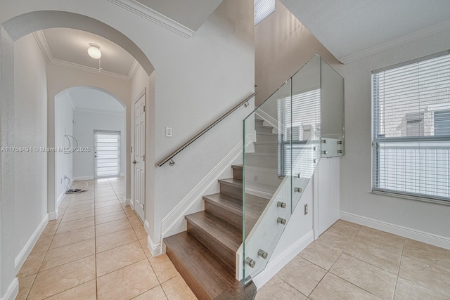 staircase featuring ornamental molding, tile patterned flooring, arched walkways, and baseboards