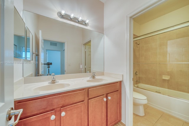 bathroom featuring tile patterned flooring, a sink, toilet, and double vanity