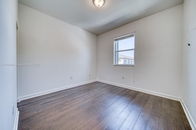 unfurnished room with dark wood-type flooring and baseboards