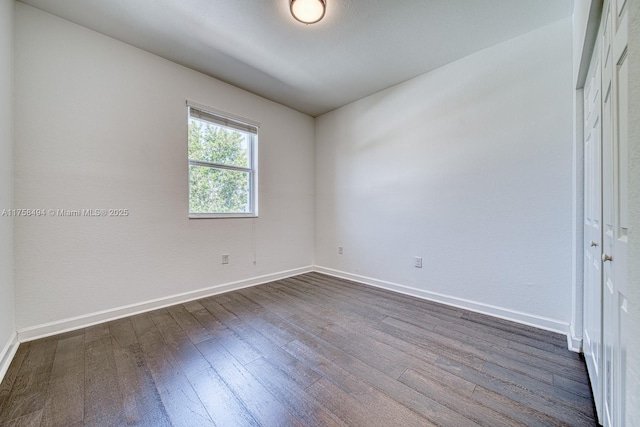 unfurnished room with dark wood-type flooring and baseboards