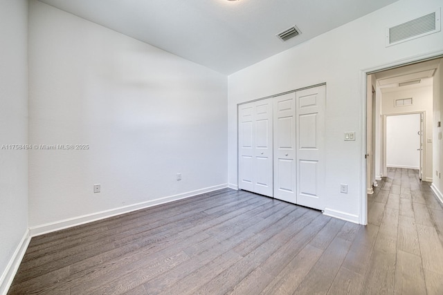 unfurnished bedroom featuring wood finished floors, visible vents, and baseboards