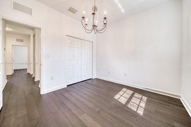 unfurnished bedroom featuring visible vents, dark wood finished floors, baseboards, and an inviting chandelier