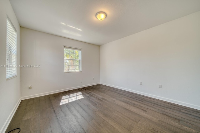 spare room featuring dark wood-type flooring and baseboards