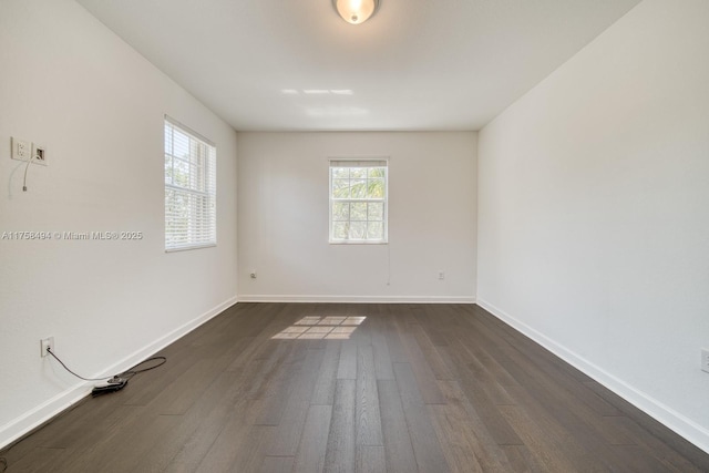 unfurnished room featuring baseboards and dark wood-type flooring