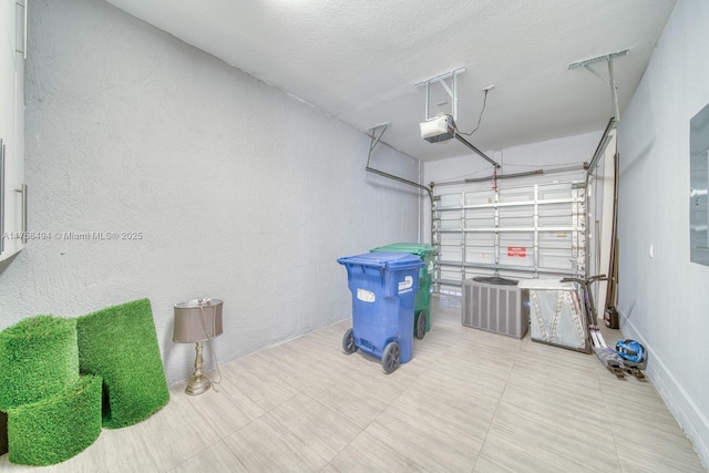 garage featuring a textured wall, central AC, and a garage door opener