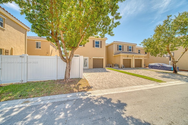 view of front of home with a tile roof, fence, driveway, and stucco siding