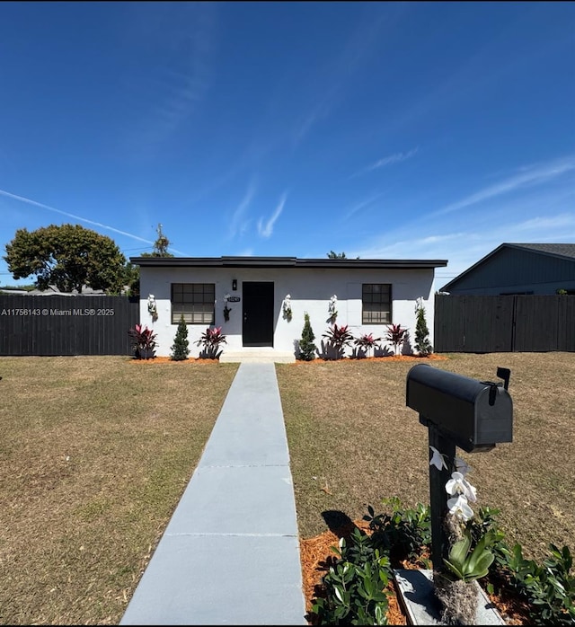 view of front of property with a front yard, fence, and stucco siding