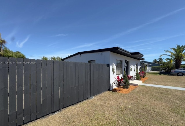 view of home's exterior featuring fence, a lawn, and stucco siding