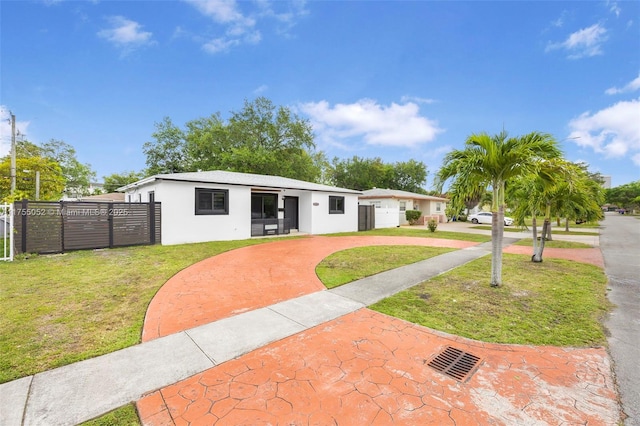 view of front of house featuring a front lawn, fence, and stucco siding