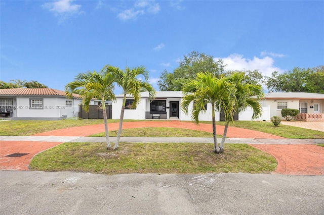 view of front of property with a front yard, decorative driveway, and fence