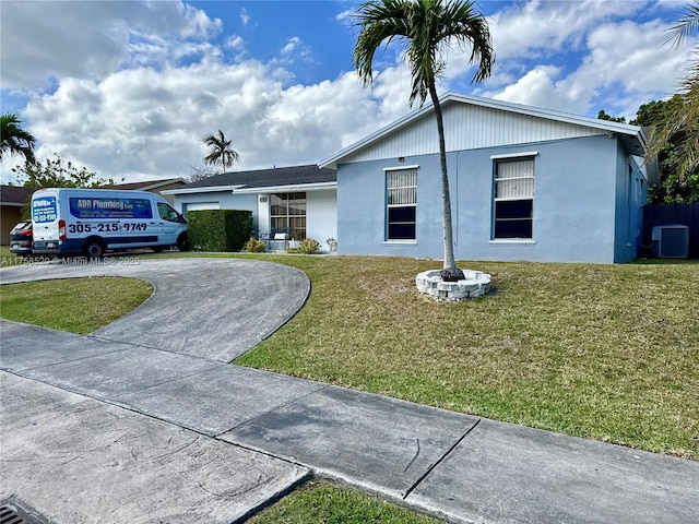 ranch-style home with driveway, a front yard, cooling unit, and stucco siding