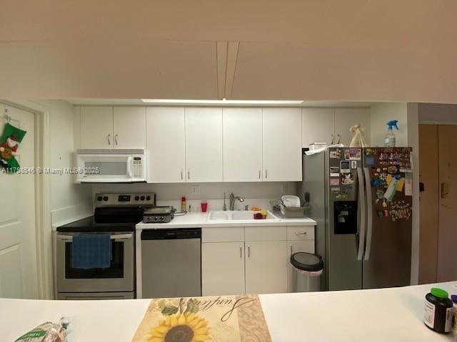 kitchen featuring light countertops, appliances with stainless steel finishes, a sink, and white cabinetry