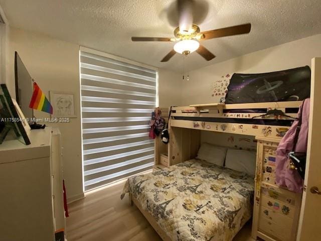 bedroom with ceiling fan, a textured ceiling, and wood finished floors