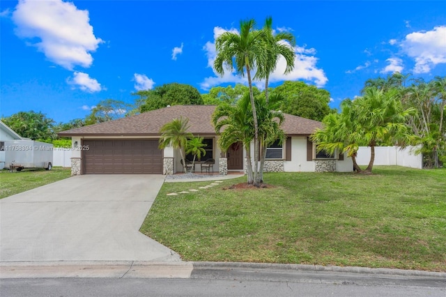 ranch-style home featuring concrete driveway, stone siding, an attached garage, fence, and a front yard