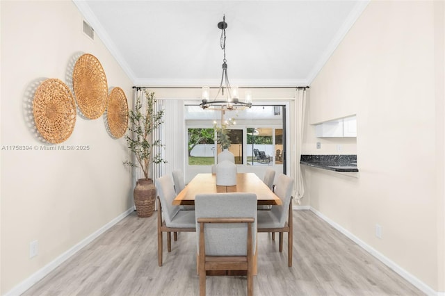 dining room featuring crown molding, visible vents, an inviting chandelier, light wood-style floors, and baseboards