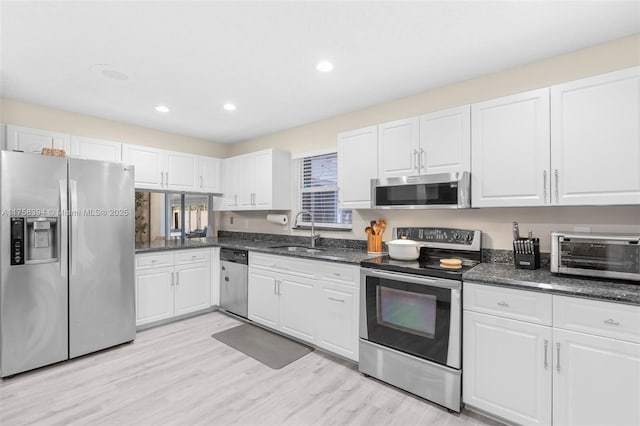 kitchen with appliances with stainless steel finishes, white cabinetry, and a sink