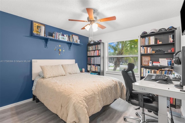 bedroom featuring a textured ceiling, wood finished floors, a ceiling fan, and baseboards