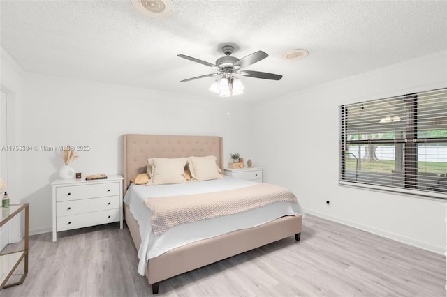 bedroom with a textured ceiling, ornamental molding, light wood-style flooring, and baseboards