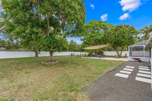 view of yard with glass enclosure, a fenced backyard, and a patio area