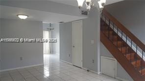 tiled empty room featuring stairway and baseboards