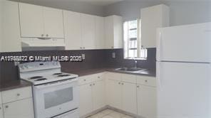 kitchen featuring dark countertops, white appliances, extractor fan, and a sink