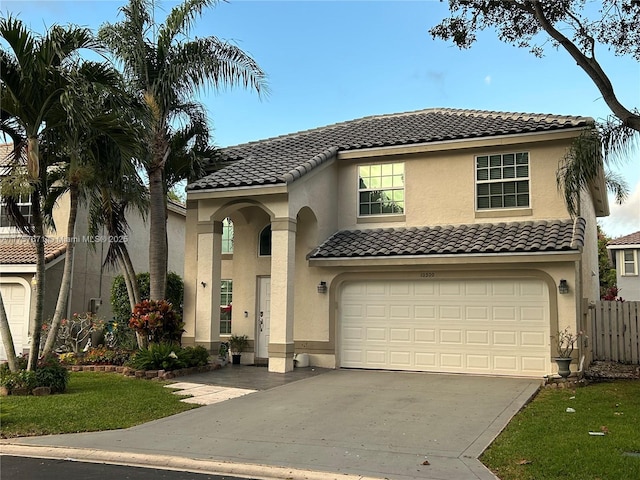 mediterranean / spanish house with a garage, concrete driveway, a tile roof, fence, and stucco siding