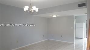 unfurnished room with a notable chandelier, baseboards, and visible vents