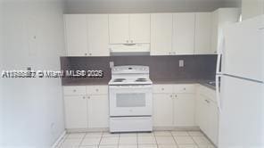 kitchen featuring under cabinet range hood, white appliances, white cabinets, and light tile patterned floors