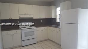 kitchen featuring under cabinet range hood, white cabinets, white appliances, and dark countertops